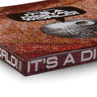 A close-up, angled shot of the corner of a book titled It's a Digital World. The book has a heavily textured cover with a red, orange, and yellow woven pattern. The title is in white font inside a black speech bubble, positioned over a black-and-white illustration of a shell fossil. The spine and edge of the book are visible against a white background.