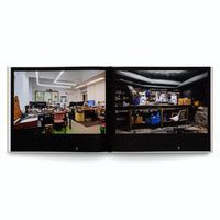 An open book on a white background displays a two-page spread with photographs of contrasting workspaces. On the left is a brightly lit, cluttered modern office or electronics lab. On the right is a dark, industrial-looking basement workshop with a workbench, speakers, and exposed pipes on the ceiling.