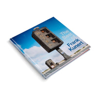 A square hardcover book titled The Best of Frank Kunert, shown at an angle on a white surface. The cover features a surreal photograph of a tall, brutalist concrete structure shaped like a waffle iron on a pillar, with the word HOTEL spelled out vertically. The structure stands by a road in a sandy landscape under a blue sky.