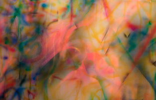 An abstract close-up image showing a riot of soft-focus, spray-painted colors. Warm hues of pink, orange, and yellow blend and overlap with cooler streaks of green and blue, creating a layered and energetic visual with a dreamlike quality.