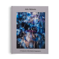 A gray, cloth-bound hardcover book titled Julie Mehretu. The cover features a vibrant abstract painting with energetic swirls of blue, purple, and white against a dark background. Below the artwork is the subtitle, A Transcore of the Radical Imaginatory.