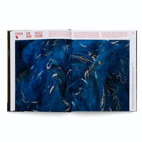 An open book features a two-page photograph showing a close-up of a tangled mass of vibrant blue fishing net. Numerous small, silvery fish are caught and entangled within the mesh. German text is printed above and alongside the image.