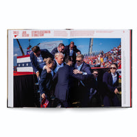 An open book displays a full-page photo with the headline ATTEMPTED ASSASSINATION OF DONALD TRUMP. The photograph shows Donald Trump with a bloodied right ear being urgently surrounded and rushed off a rally stage by several Secret Service agents in dark suits. The agents form a protective barrier around him in front of a crowd and American flags.