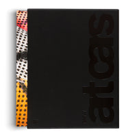 An overhead shot of the book BMW art cars in its matte black slipcase. The title art cars is debossed vertically in large, glossy black letters. The colorful spine of the book, featuring red, orange, and white sections with black polka dots, is visible on the left side.