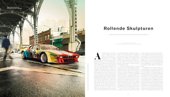 A two-page magazine spread featuring a photograph of Andy Warhol's 1979 BMW M1 Art Car. The car, adorned with vibrant, painterly swaths of primary colors and the racing number 76, is positioned on a wet street in New York City beneath a large metal overpass. The right page displays the article's title, Rollende Skulpturen, and text in German.