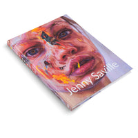 An angled shot of the art book Jenny Saville on a white background. The cover features an expressive, close-up portrait of a woman's face, painted with thick, textured brushstrokes in vibrant reds, pinks, and oranges.