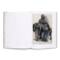An open art book on a white surface. The right page features an expressive, sketchy artwork in charcoal and blue tones depicting a seated figure holding a limp body across their lap in a modern Pietà composition. The left page is mostly blank, with the caption Pietà III, 2020-2021.