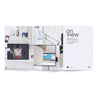 An open art catalog on a white surface. The left page shows a digital collage of layered images, including computer screenshots, a gallery interior, and a portrait. The right page is a title page with the words on view, Begegnungen mit dem Fotografischen, and Encounters with the Photographic.