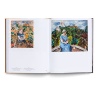 An open art book on a white background, displaying a two-page spread. On each page is a colorful, expressive painting of a woman in a blue dress sitting on a terrace, holding a white bird. Other white birds fly around her against a backdrop of a green, hilly landscape with a village. The painting on the left is a vertical study, while the one on the right is a more finished, square composition.
