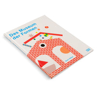 An angled view of the book Das Museum der Formen by Sven Völker, resting on a white surface. The cover features a playful, graphic illustration of a house-like structure made from a red brick pattern, with various colorful geometric shapes serving as its features and decorations.