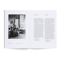A high-angle shot of an open art book on a white surface. The left page displays a black-and-white photograph of artist Hilma af Klint seated in her studio. The right page contains the book's foreword, presented in two columns in English and German.