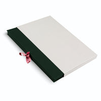 A flat, rectangular two-tone presentation box on a white surface. The dark green inner box is partially enclosed by a textured off-white sleeve, and a small, dusty pink ribbon pull extends from the side.