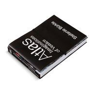 A black hardcover book, Atlas of Imaginations of Venice by Stefanie Bürkle, is shown at an angle on a white background. The book features white text, a black elastic closure, and colorful page edges, hinting at its photographic content.