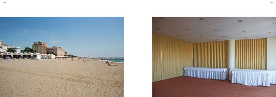 A book spread showing two contrasting photographs. On the left, a sunny, wide shot of a sandy beach filled with people, with hotels and the ocean in the background under a clear blue sky. On the right, an empty, windowless banquet room with red patterned carpet, beige curtains, and long tables covered in white pleated cloths.