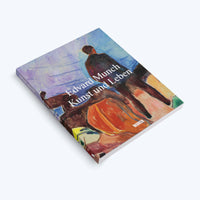 A paperback book titled Edvard Munch Kunst und Leben lies at an angle on a white surface. The cover features an Expressionist painting of a figure seen from behind, looking out over a landscape with a colorful, swirling sky. The title is printed in white letters over the artwork.